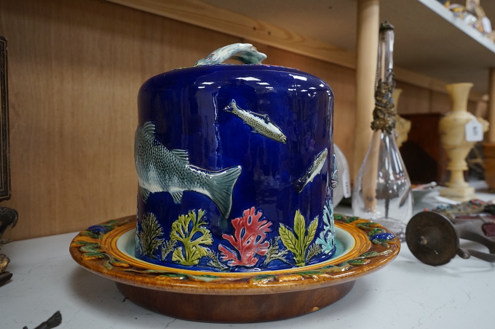 A Victorian majolica cheese dome decorated with fish and seaweed, and a later dish, dome 23cm high, 23cm diameter, dish 24cm internal diameter